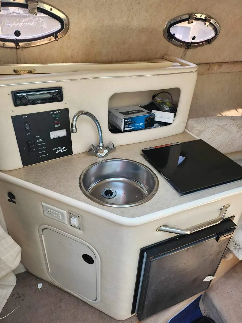 Slide: The Image of 2001 Sea Ray 240 Sundancer cabin kitchenette with sink, stove, and storage. - 9