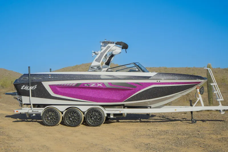 Slide: The Image of 2020 Tigé 25ZX boat on trailer, featuring a vibrant purple and black design. - 2