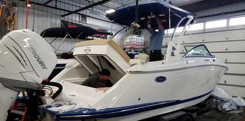 Slide: The Image of 2019 Cobalt 25SC boat in a workshop, undergoing maintenance with two people working. - 7