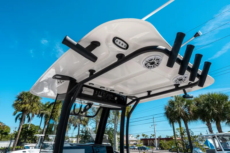 Slide: The Image of 2025 Sea Hunt Ultra 265 SE boat top with rod holders and speakers, under clear blue sky. - 22