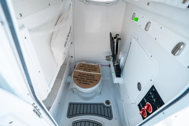 Slide: The Image of Interior of 2025 Sea Hunt Ultra 265 SE boat, featuring a compact marine toilet. - 31