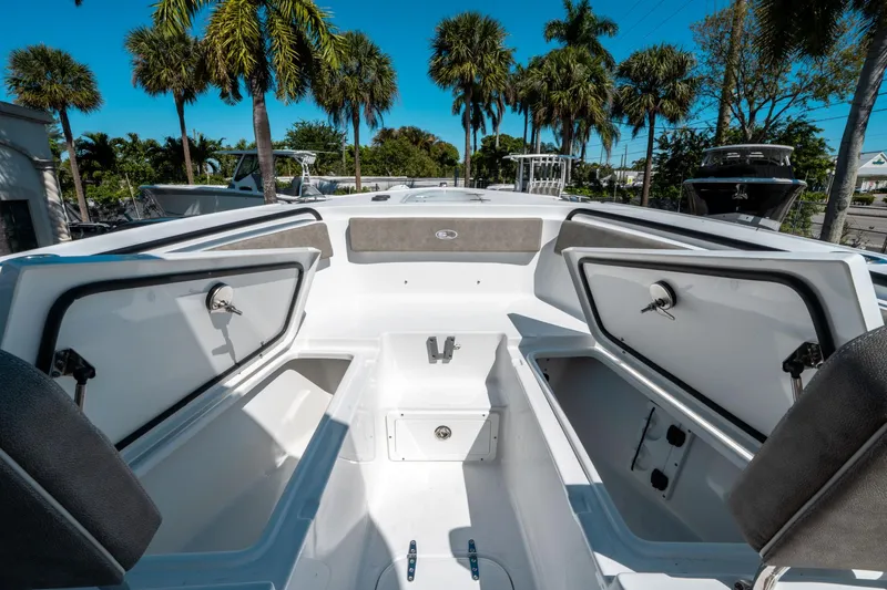 Slide: The Image of 2025 Sea Hunt Ultra 265 SE boat interior with open storage compartments, surrounded by palm trees. - 37
