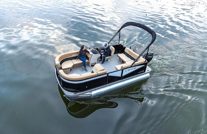 Slide: The Image of 2025 Lowe LS170 pontoon boat cruising on calm water with passengers. - 2