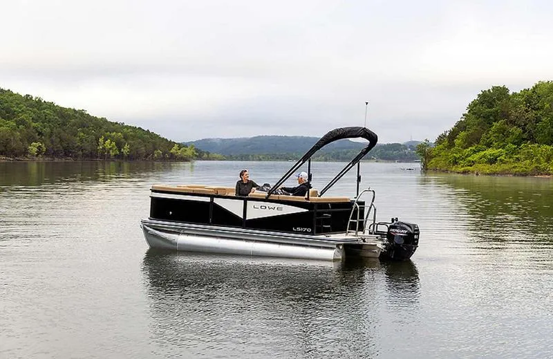 Slide: The Image of 2025 Lowe LS170 pontoon boat on a serene lake with lush green surroundings. - 4