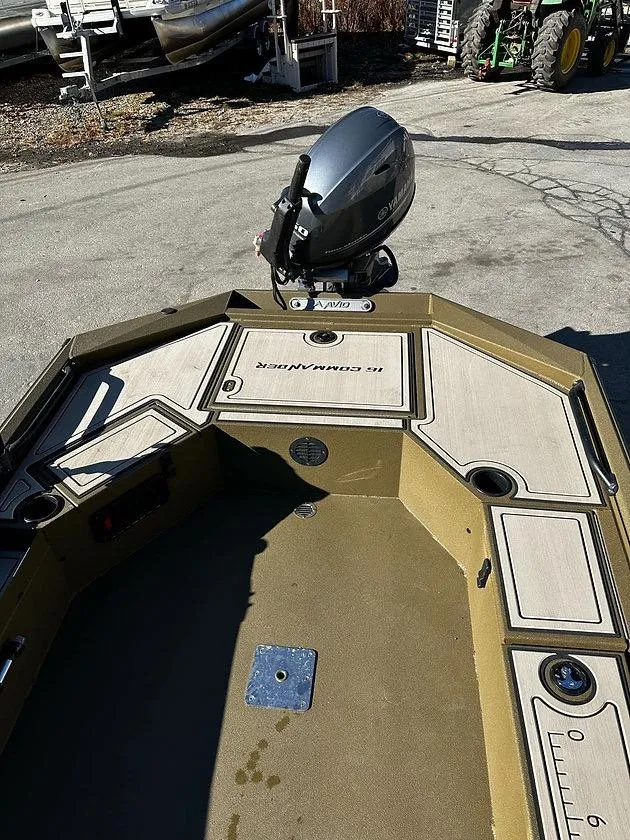 Slide: The Image of 2025 Avid 16 Commander boat with motor, parked outdoors on a sunny day. - 2