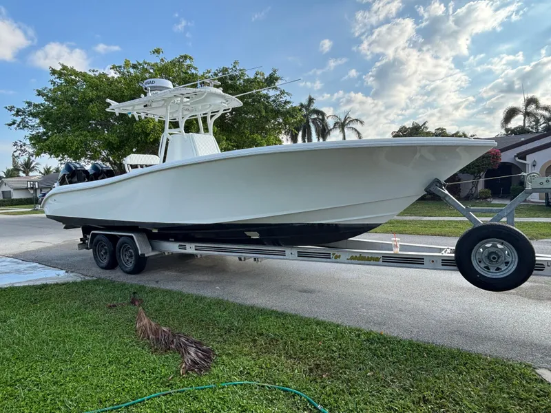 The Image of 2012 Yellowfin 29 boat on trailer, parked outdoors under a partly cloudy sky. - 0