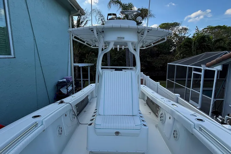 Slide: The Image of 2012 Yellowfin 29 boat with white seating and T-top, docked near a house. - 14