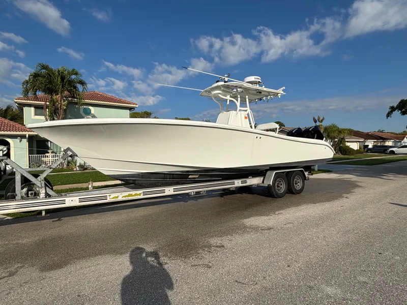 Slide: The Image of 2012 Yellowfin 29 boat on trailer, parked in residential area under clear blue sky. - 2