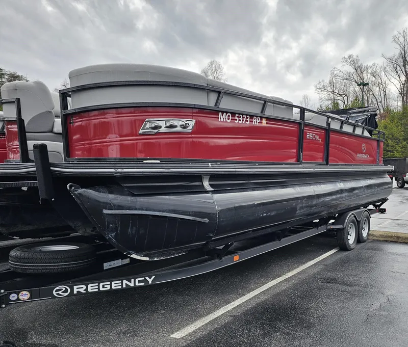 Slide: The Image of A red 2023 Regency 250DL3 pontoon boat on a trailer, ready for use. - 2