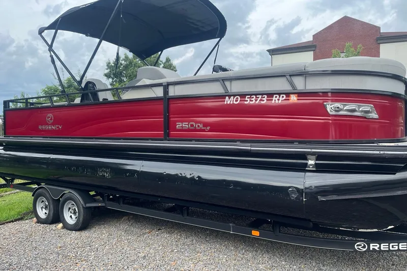 The Image of 2023 Regency 250DL3 pontoon boat with red exterior on a trailer. - 0
