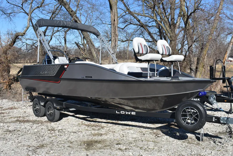 Slide: The Image of 2025 Lowe SD224 Sport Deck boat on trailer, parked outdoors. - 2