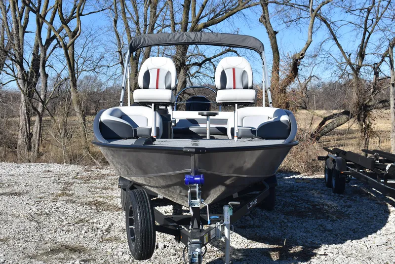 Slide: The Image of 2025 Lowe SD224 Sport Deck boat on trailer, parked outdoors in a wooded area. - 3