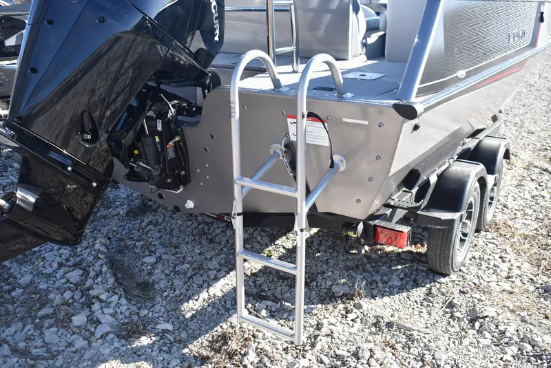 Slide: The Image of 2025 Lowe SD224 Sport Deck boat with ladder and trailer on gravel surface. - 6