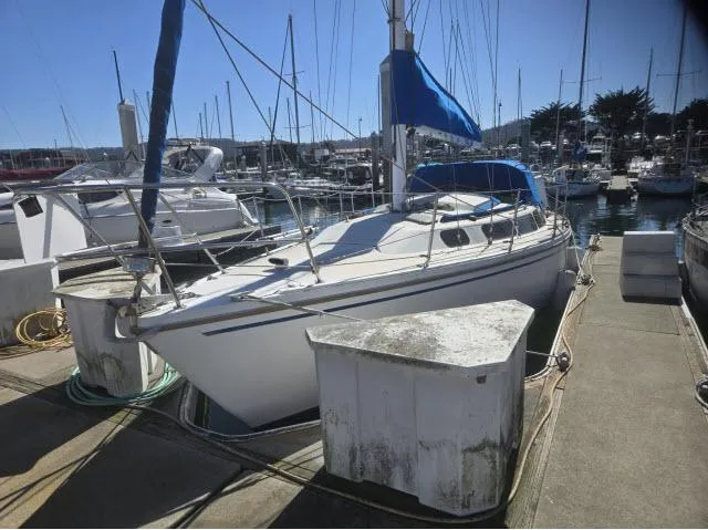 Slide: The Image of 1983 Catalina 30 sailboat docked in a marina, featuring a blue sail cover. - 1