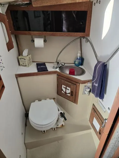 Slide: The Image of 1983 Catalina 30 boat bathroom with sink, toilet, and storage cabinets. - 10