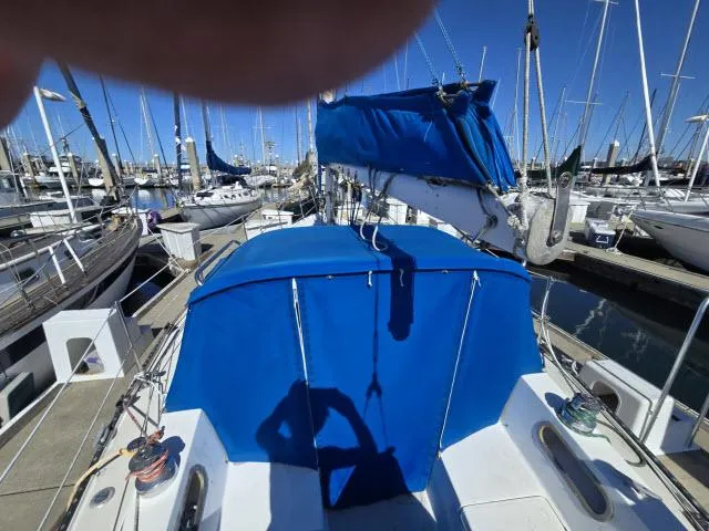 Slide: The Image of 1983 Catalina 30 sailboat with blue covers docked in a marina. - 12