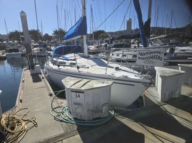 Slide: The Image of 1983 Catalina 30 sailboat docked at marina, surrounded by other boats, with blue sails. - 18
