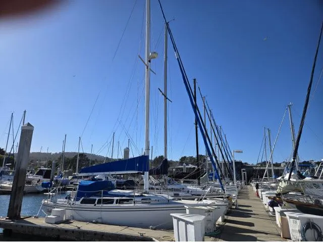 Slide: The Image of 1983 Catalina 30 sailboat docked in a marina under clear blue skies. - 19