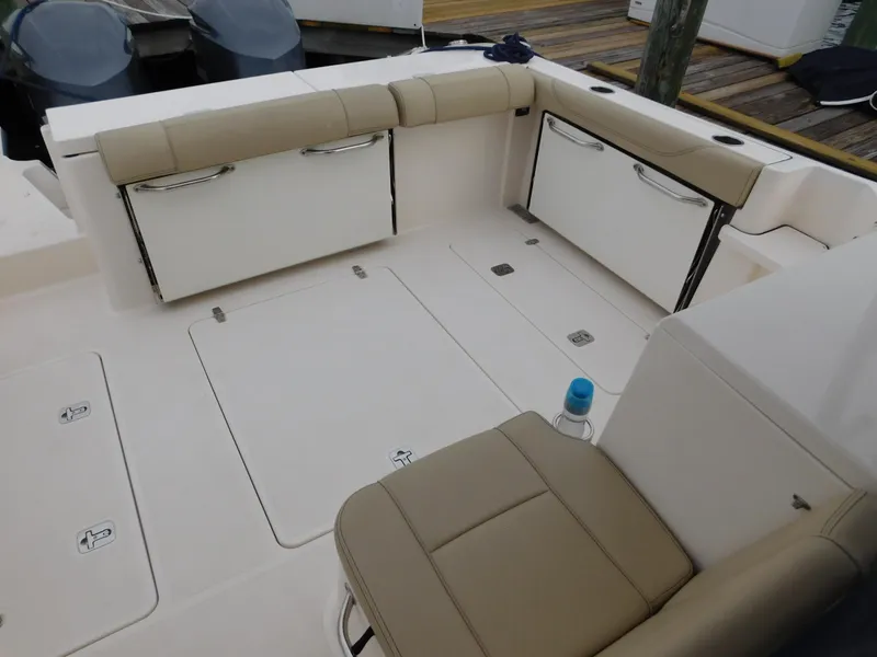 Slide: The Image of 2018 Pursuit OS 325 Offshore boat interior with beige seating and storage compartments. - 24