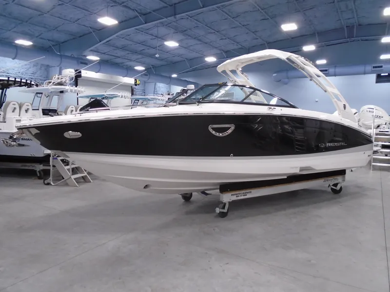 The Image of 2025 Regal LX6 boat in showroom, sleek design, black and white exterior. - 19
