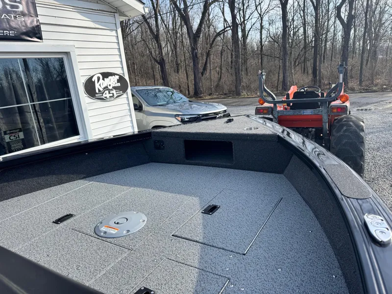 Slide: The Image of 2025 Crestliner 1850 Fish Hawk WT JS boat interior with storage compartments, parked near a building. - 6