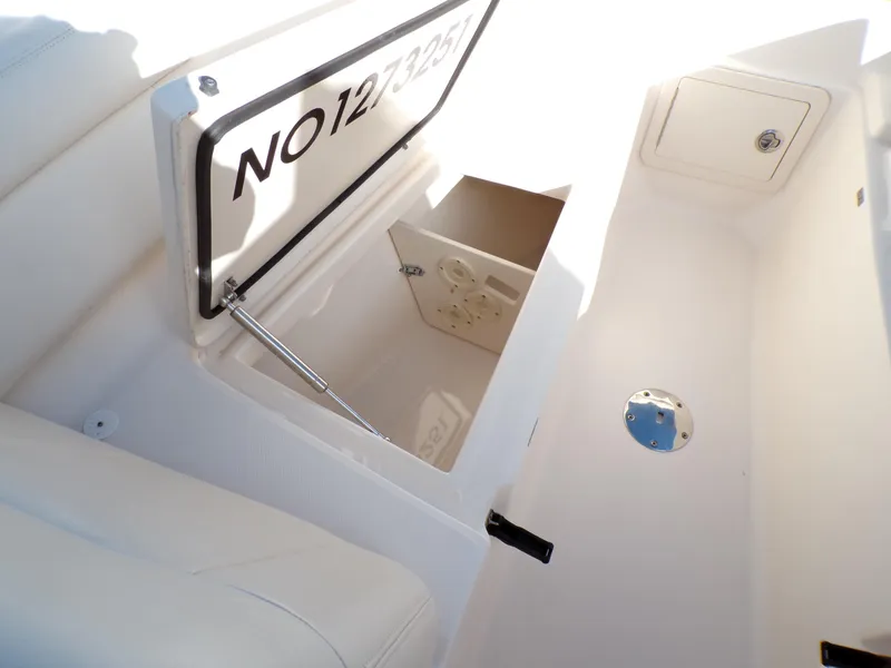 Slide: The Image of 2016 Grady-White Freedom 275 boat storage compartment with open hatch and visible registration number. - 23