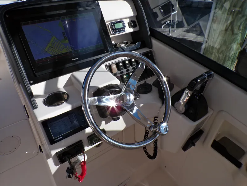 Slide: The Image of 2016 Grady-White Freedom 275 boat dashboard with steering wheel and navigation controls. - 39