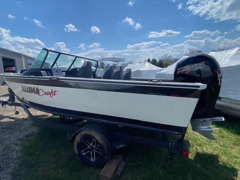 Slide: The Image of 2023 Alumacraft Trophy 185 boat on trailer under a clear blue sky. - 1