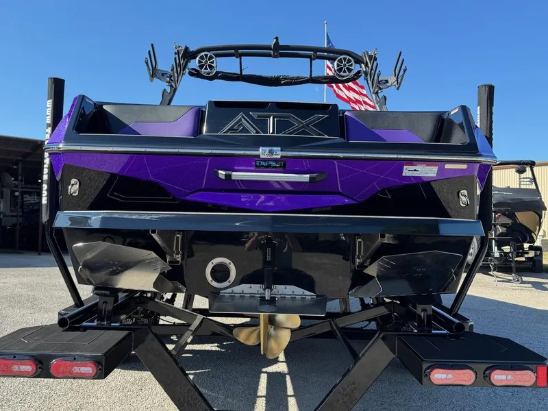 Slide: The Image of 2025 ATX Surf Boats 22 Type-S, rear view, purple and black design, on trailer. - 5
