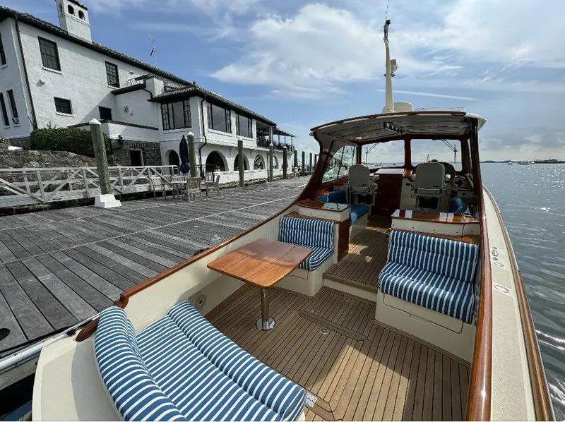 Slide: The Image of 2018 Hinckley Picnic Boat 37 MKIII docked, featuring striped seating and wooden deck. - 10