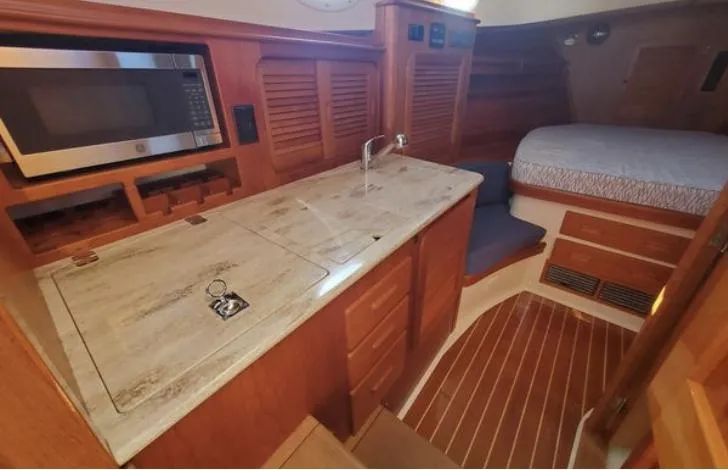 Slide: The Image of 2018 Hinckley Picnic Boat 37 MKIII interior with kitchenette and bed, featuring wood finishes. - 19