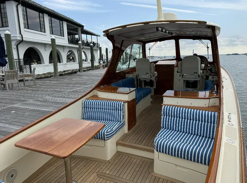 Slide: The Image of 2018 Hinckley Picnic Boat 37 MKIII with striped seating, docked by a waterfront building. - 11