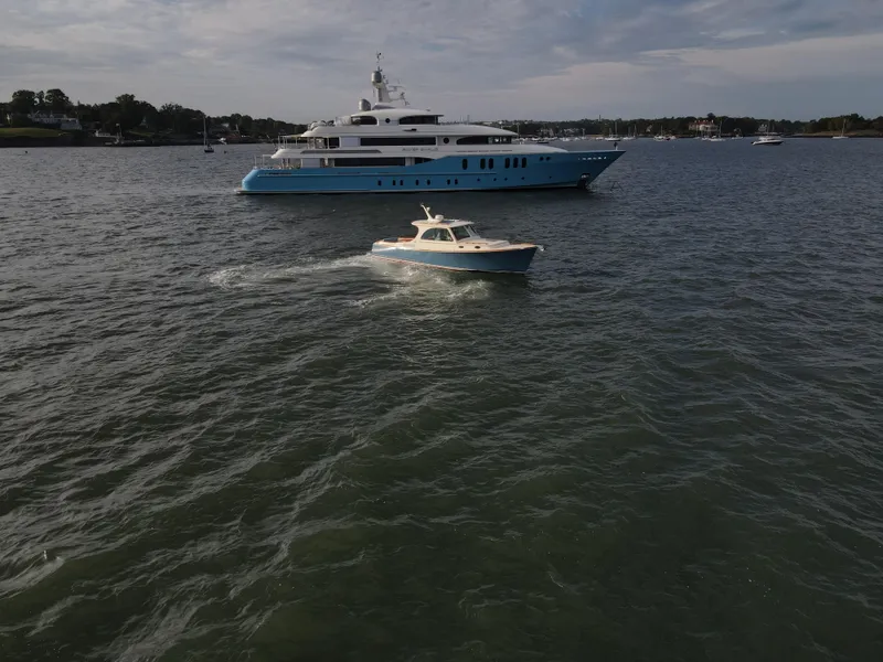 Slide: The Image of 2018 Hinckley Picnic Boat 37 MKIII cruising near a large yacht on a calm sea. - 2