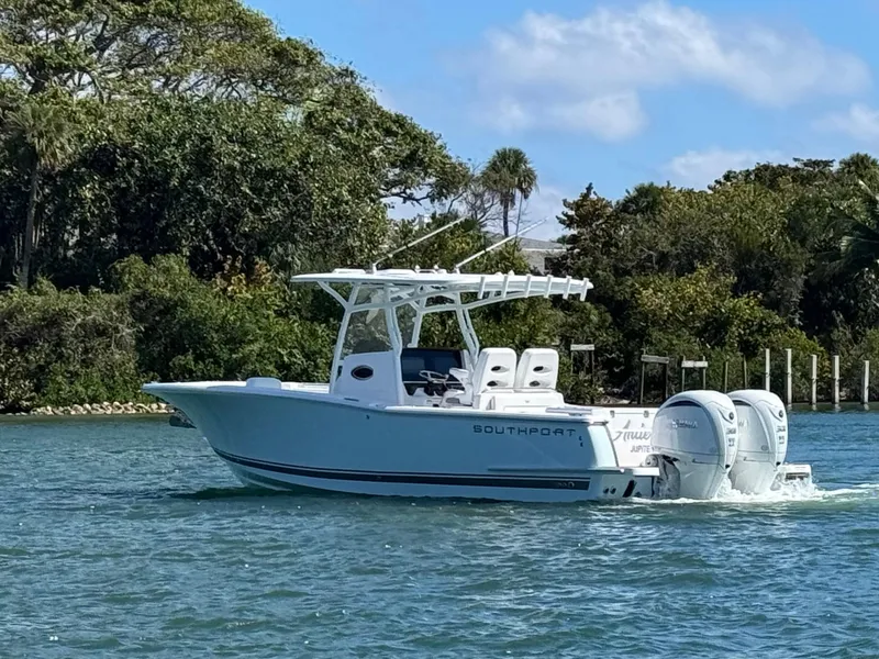 Slide: The Image of 2024 Southport 30 FE boat cruising on a sunny day, surrounded by lush greenery. - 10