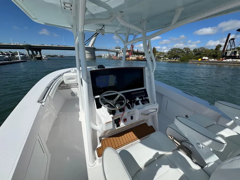 Slide: The Image of 2024 Southport 30 FE boat interior with steering console, docked by a scenic waterfront. - 16