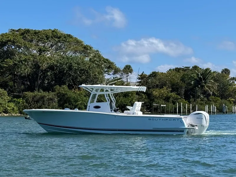 Slide: The Image of 2024 Southport 30 FE boat cruising on a sunny day near lush shoreline. - 2
