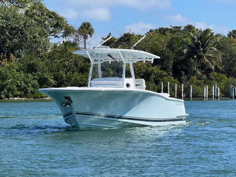 Slide: The Image of 2024 Southport 30 FE boat cruising on a sunny day, surrounded by lush greenery. - 5