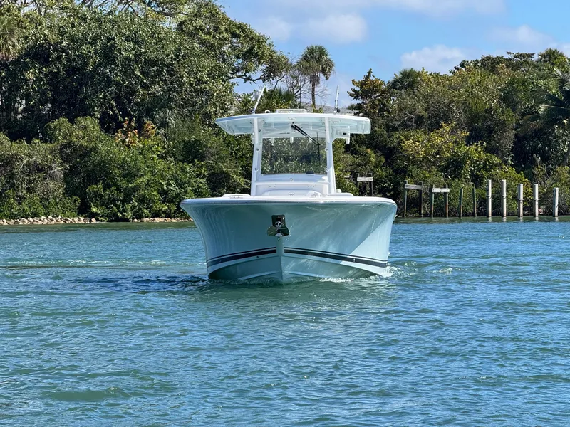 Slide: The Image of 2024 Southport 30 FE boat cruising on a sunny day, surrounded by lush greenery. - 6