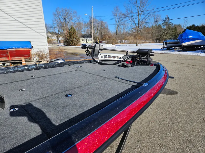 Slide: The Image of 2025 Skeeter ZXR21 boat with red trim, parked outdoors on a sunny day. - 6