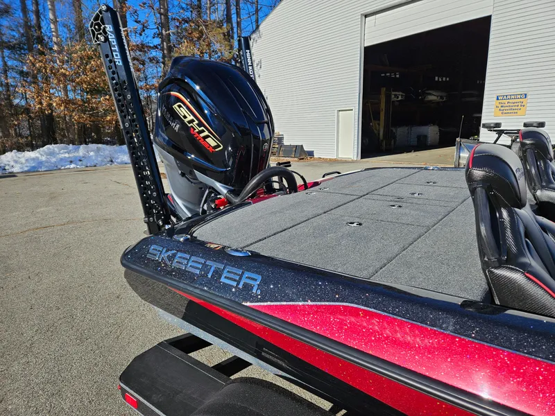 Slide: The Image of 2025 Skeeter ZXR21 boat with powerful engine, parked outside a garage on a sunny day. - 7