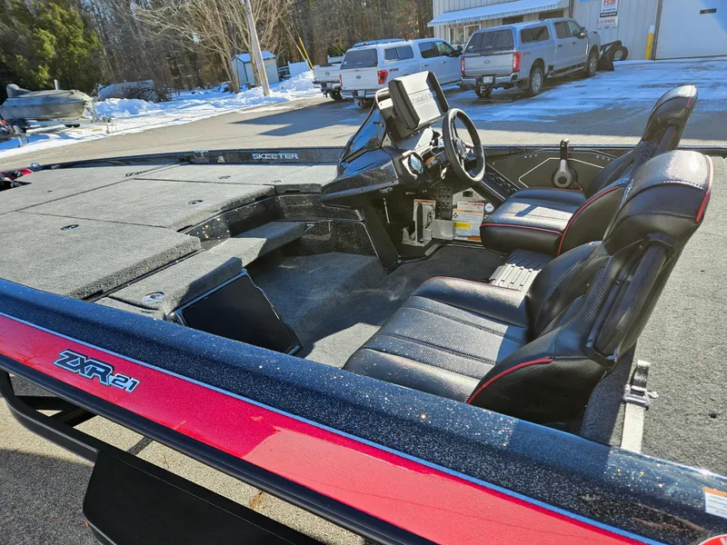 Slide: The Image of 2025 Skeeter ZXR21 boat interior with black seats and steering wheel, parked outdoors. - 8
