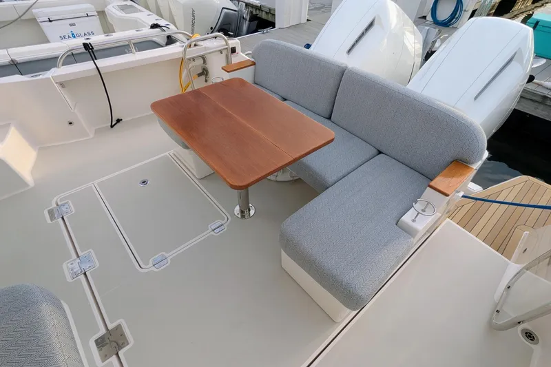 Slide: The Image of 2024 Back Cove 39O boat with cushioned seating and wooden table on deck. - 13