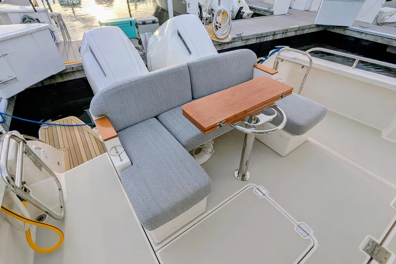 Slide: The Image of 2024 Back Cove 39O boat with cushioned seating and wooden table on deck. - 14