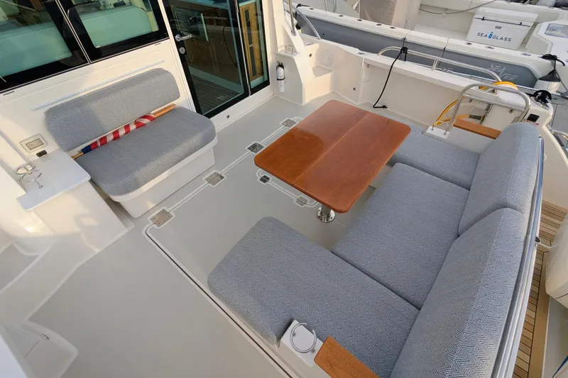 Slide: The Image of 2024 Back Cove 39O boat interior with cushioned seating and wooden table. - 16