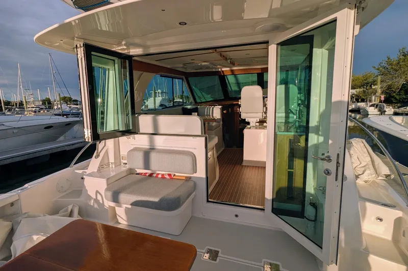 Slide: The Image of 2024 Back Cove 39O yacht interior with open doors, showcasing seating and helm area. - 17