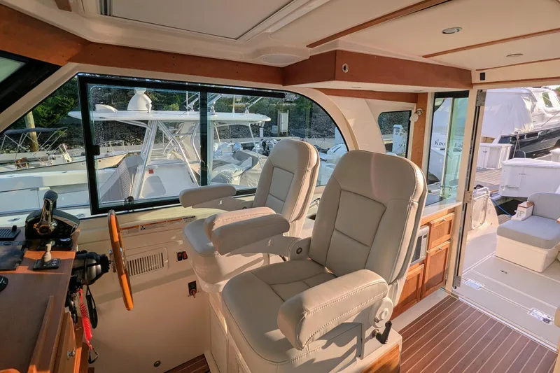 Slide: The Image of 2024 Back Cove 39O yacht interior with helm seats and wooden accents. - 19