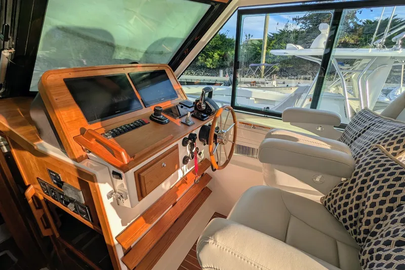 Slide: The Image of 2024 Back Cove 39O helm with modern controls, wooden accents, and comfortable seating. - 21