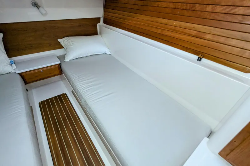 Slide: The Image of 2024 Back Cove 39O cabin interior with wooden accents and white bedding. - 40