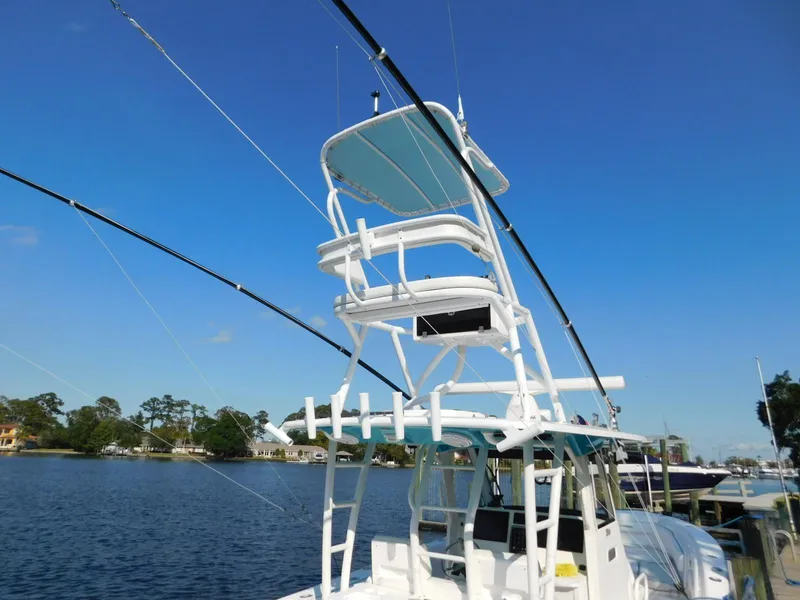 Slide: The Image of 2016 Everglades 355 Center Console boat with tower, docked by a serene lake. - 5