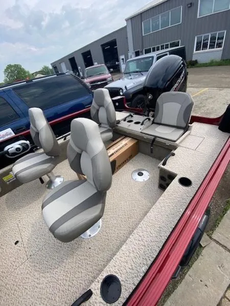 Slide: The Image of 2022 Alumacraft Competitor 165 CS boat interior with seating and motor, parked outdoors. - 4